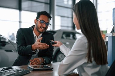 Kadın galeride danışman olarak çalışıyor. Yeni otomobilin anahtarlarını almak.