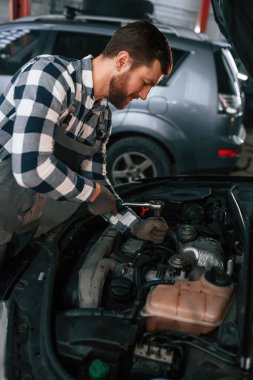 Araba detayları. Aracı tamir ediyorum. Üniformalı adam araba galerisinde çalışıyor..