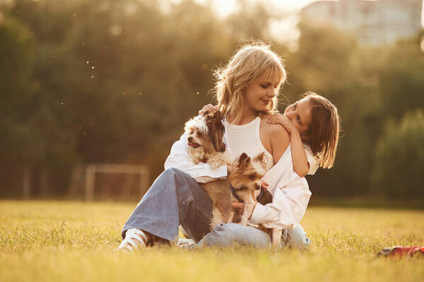 Embracing the mother. Beautiful mother with her little daughter and dogs are on the summer field together.