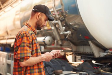 Parlak güneşli bir gün. Gündelik giysiler içindeki genç kamyon şoförü..