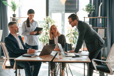 Meşgul işçiler masanın yanında. Bir grup iş adamı modern ofiste..