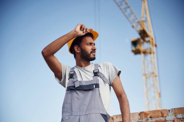 Mola veriyoruz. Vinç ve mavi gökyüzüne karşı duruyor. Yakışıklı Hintli adam şantiyede..