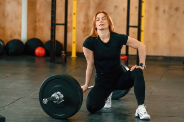 Halterle yerde oturuyor. Güzel, güçlü kadın spor salonunda..