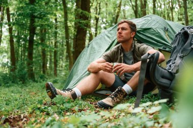 Bir bardak suyla. Çadırın yanında oturuyor. Yaz ormanında bir turist. Keşif ve eğlence kavramı.