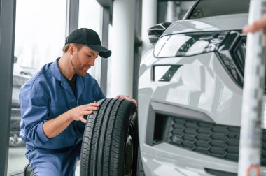 Lastiği değiştiriyorum. Mavi üniformalı adam araba servisinde çalışıyor..