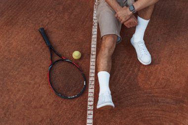 Manzarayı kapat. Raketle. Genç adam güneşli bir günde tenis kortunda..