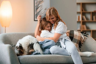 Kanepede. Anne kızıyla ve sevimli köpeğiyle evcil odada..