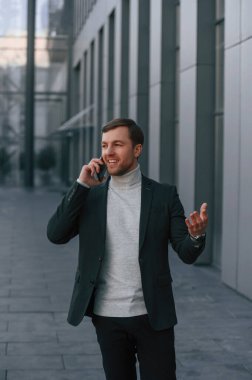 Telefonla konuşuyorlar. Resmi kıyafetli yakışıklı dışarıda, iş binasının yanında..