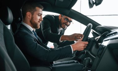 Otomobilin içini müşteriye gösteren adam.