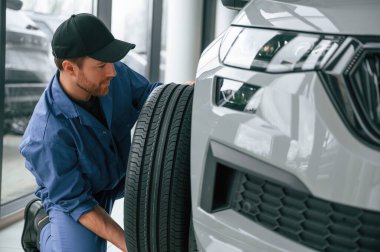 Lastiği değiştiriyorum. Mavi üniformalı adam araba servisinde çalışıyor..