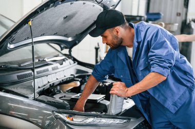 Yağı değiştirme süreci. Otomobil tamircisi garajda çalışıyor. Onarım servisi.