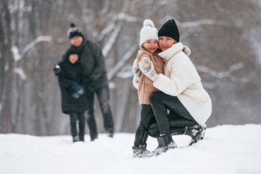 Anne ve kızı birbirlerine bakıyorlar. Mutlu aile dışarıda, kışın birlikte kar tatilinin tadını çıkarıyorlar..