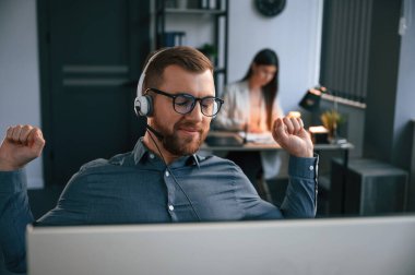 Adamın arkasında bir kadın var. Modern ofiste iki çalışan birlikte çalışıyor..