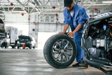 Yeni lastik, hareket ettiriyor. Otomobil tamircisi garajda çalışıyor. Onarım servisi.