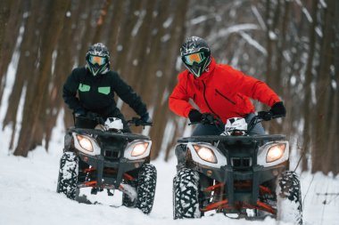 Ekstrem spor anlayışı. Kış ormanında iki kişi ATV kullanıyor..