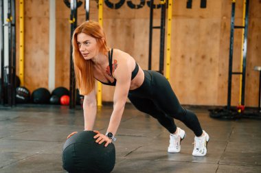 Yumuşak top kullanarak şınav çekiyorsun. Güzel, güçlü kadın spor salonunda..