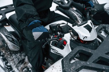 Ellerin ve aracın ön kısmının görüntüsünü kapat. İnsan kış ormanlarında ATV 'ye biniyor..