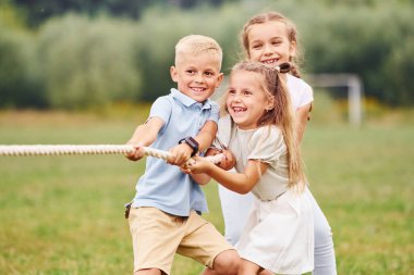Gülümsüyor, savaş oyunu oynuyor. Çocuklar gündüz vakti sahada eğleniyorlar..