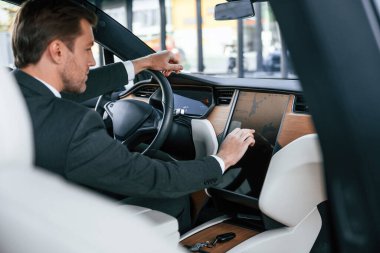 Dikiz aynası. Takım elbiseli bir işadamı elektrikli arabasını kullanıyor..