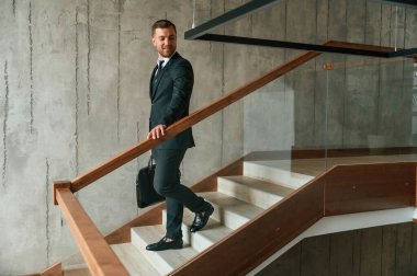 Çantası ellerindeydi. Takım elbiseli ve kravatlı adam merdivenlerde..