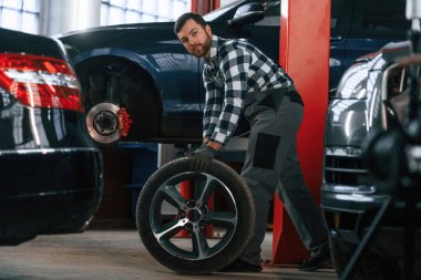 Adam direksiyonu hareket ettiriyor. Çalışan araba galerisinde çalışıyor..