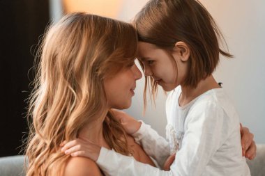 Yan görüş, birbirimizi kucaklamak. Anne ve küçük kızı evdeki odada birlikteler..