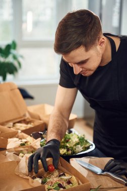 Hamburgere sebze ekliyorum. Adam karton ekolojik kutulara yiyecek koyuyor. İçeride, restoranda..