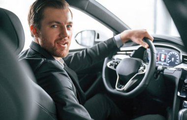 Modern otomobilde duran resmi iş kıyafetleri içindeki bir adamın portresi..