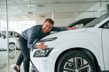 Yeni otomobili kucaklıyorum. Yakışıklı araba galerisi çalışanı elektrikli araçla çalışıyor..