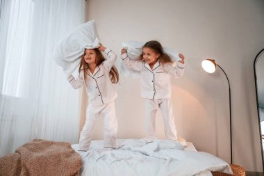 Yurt içi odada, yatağın üstünde. Yastık savaşı oynuyoruz. İki küçük kız yurt odasında birlikte eğleniyorlar..