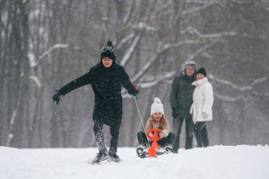 Kızak sürerek eğleniyoruz. Mutlu aile dışarıda, kışın birlikte kar tatilinin tadını çıkarıyorlar..