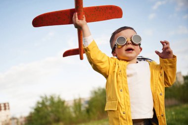 Kırmızı renkli oyuncak uçak. Küçük çocuk yaz sahasında oynuyor..