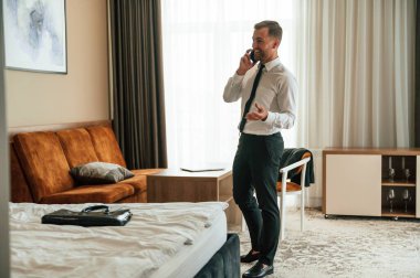 Telefon görüşmesi. İş adamı içeride, otel odasında..