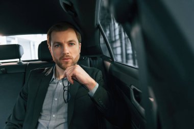 Rahat modern bir otomobilde. Resmi iş elbiseli adam..