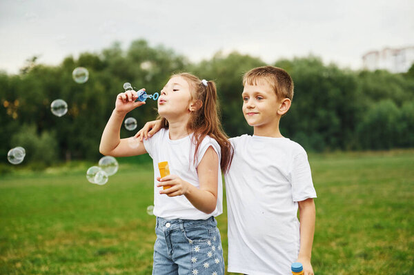 Boy and girl are together having fun on the field at daytime.