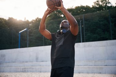 Doğal ışıklandırma. Genç siyah adam basketbol topuyla dışarıda..