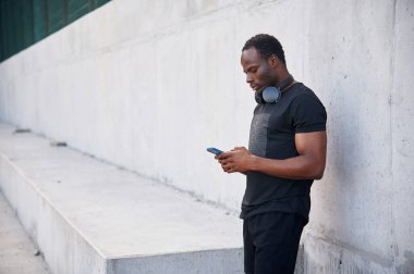 Kulaklıkla. Yakışıklı siyah adam gündüz vakti dışarıda poz veriyor..