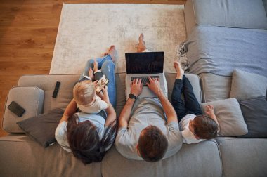 Üst görünüm, dizüstü bilgisayar. İki küçük çocuklu ebeveynler evcil odada birlikteler..