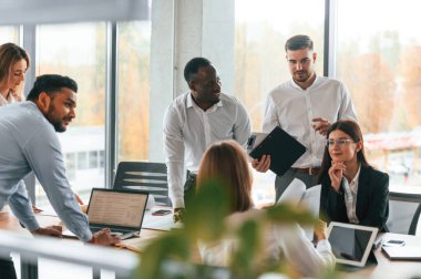 Ekip meşgul ve proje için fikirleri getiriyorlar. Bir grup ofis çalışanı içeride birlikte..