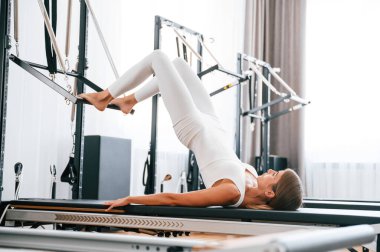 Uzan ve bacaklarını aç. Spor salonundaki genç kadın egzersiz yapıyor..