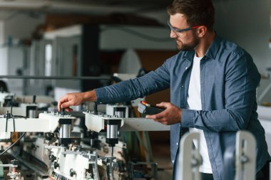 Makineyle çalışmak. Yakışıklı adam ekolojik kutular üreten fabrikada..