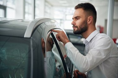 Cilalı yüzeye bakıyorum. Resmi giyinen işçi oto kuaföründe..