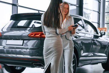 Tableti tutuyorum. Kadın müdür kadın müşteriye araba galerisinde yardım ediyor..