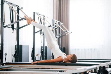 Uzan ve bacaklarını aç. Spor salonundaki genç kadın egzersiz yapıyor..