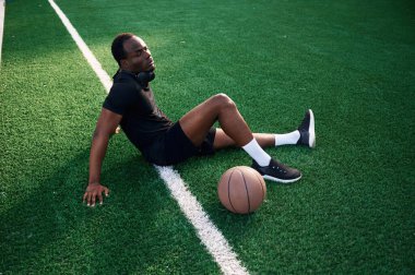 Oturup dinleniyorum. Genç siyah adam basketbol topuyla dışarıda..