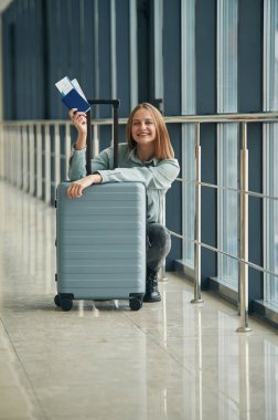 Havaalanı koridorunda bekliyor. Bagajlı genç bayan..