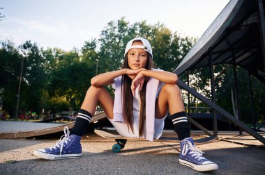 Parkta güzel bir yaz zamanı, oturmak. Dışarıda kaykaylı mutlu küçük kız.