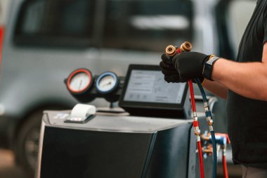 Ellerinde kablolarla. Adam otomobil tamirhanesinde çalışıyor..