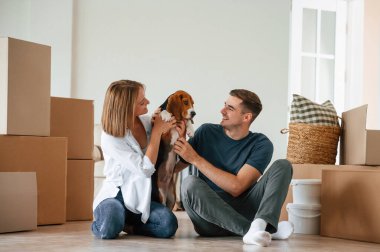 Oturup köpekle oynamak. Genç çift yeni evine taşınıyor..