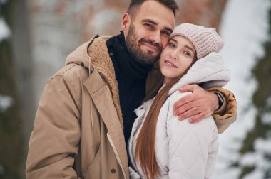 Neşeli yüz ifadesi. Güzel bir çift kış ormanında yürüyüşe çıktı..